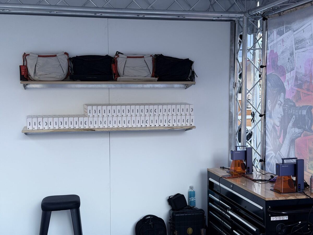 Folded printed tees and custom messenger bags arranged on a Merch Troop event display shelf