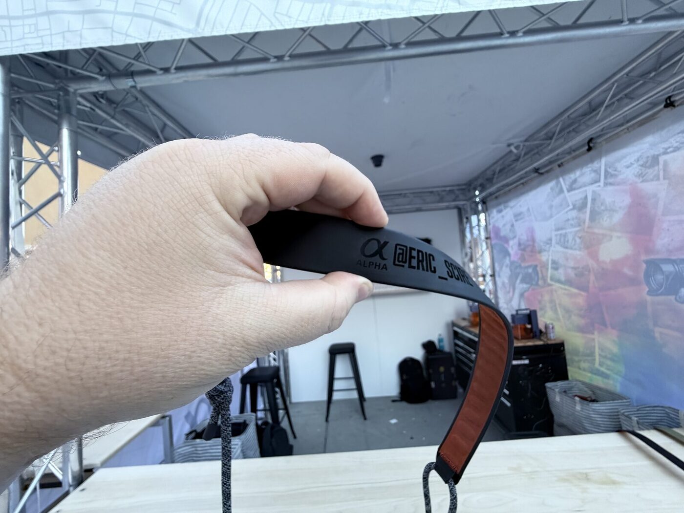 A gloved hand holding a finished embroidered patch at an outdoor live-printing setup